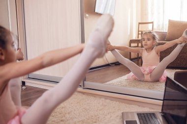 Pretty young ballerina practicing classic choreography during online class in ballet school, social distance during quarantine, self-isolation, online education concept clipart