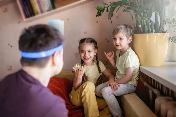 Happy adult father playing at board game with his two kids in domestic interior, family values actually, stay at home, life during quarantine