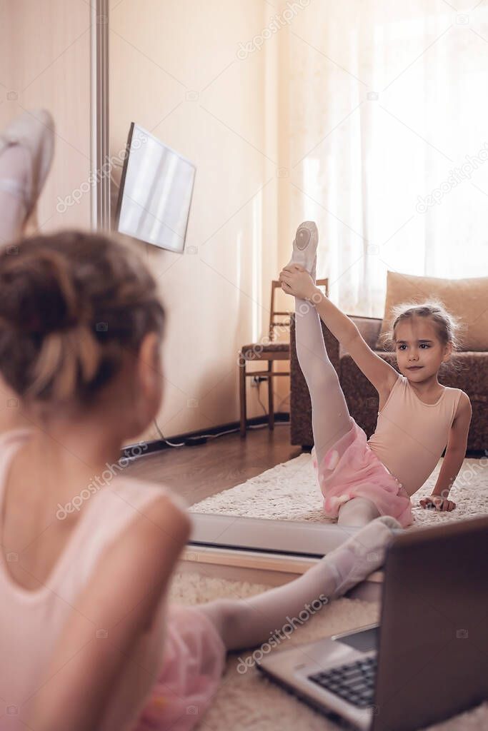 Pretty young ballerina practicing classic choreography during online class in ballet school, social distance during quarantine, self-isolation, online education concept