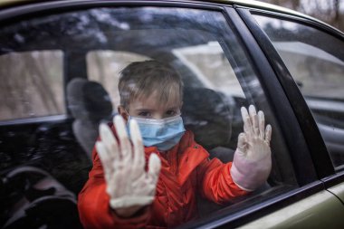 Little boy wearing respirator mask and medical gloves looking through a car window, stop travel, self-isolation during quarantine, stay safe concept clipart
