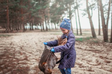 Genç gönüllüler, erkek ve kız kardeşler babalarıyla birlikte sahildeki ormanları temizliyor ve çöpleri torbaya dolduruyorlar. Gezegen kavramını ve ekoloji sorununu kurtarıyorlar.