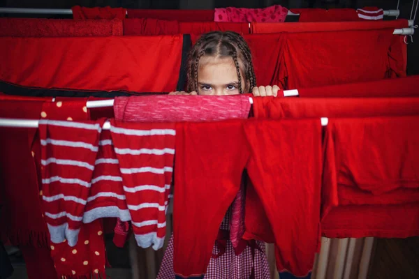 Cute little girl helping to hang red clothes after washing, keep like colors together to prevent color from fading, chores tips, indoor lifestyle