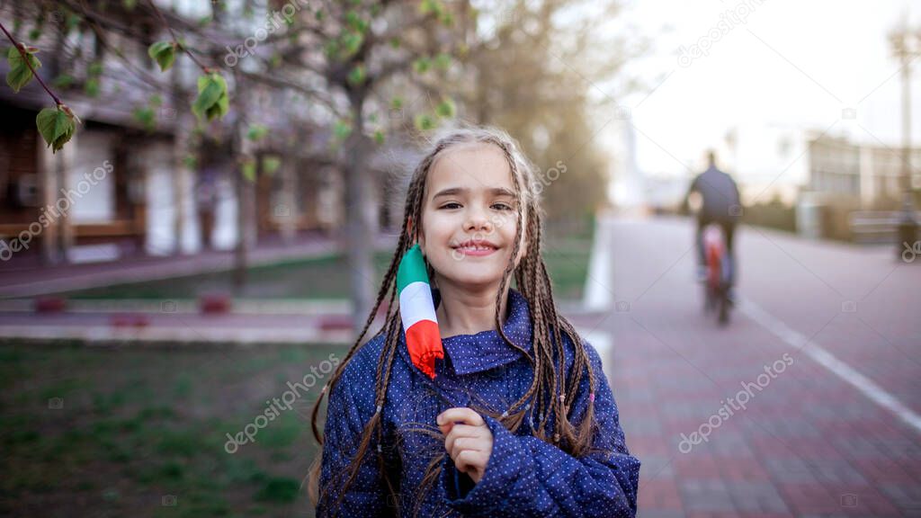 Happy little girl wearing off the respirator medical mask in national Italy colors because of the end of quarantine in the country, happiness and hope, stop virus spreading, outdoor lifestyle