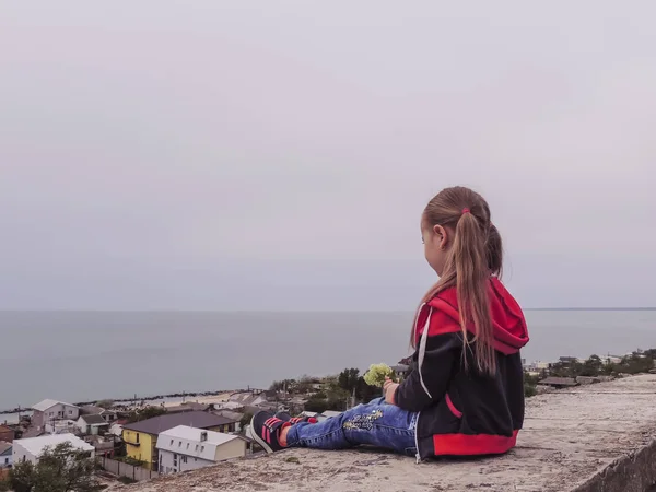 一个美丽的女孩坐在那里, 看着城市和大海. — 图库照片