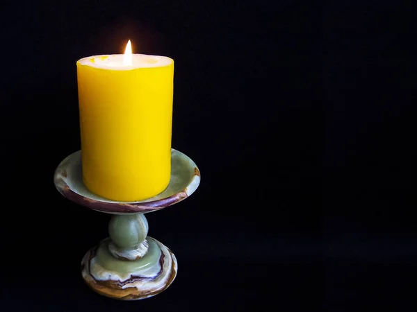 Luminaire candle holder Onyx with yellow candle on a black background