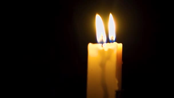 Twee kaarsen branden in het donker. Kaarsen in de kerk. Close-up. — Stockvideo