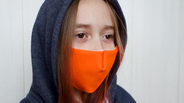 Yüzü maskeli bir genç öksürüyor. Coronavirus ve grip salgını konsepti. Kız, maske takıyor, göz kırpıyor ve etrafına bakıyor.. — Stok video