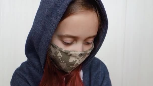 Teenager mit militärischem Mundschutz. Coronavirus und Grippeepidemie. Mädchen mit Maske blinzelt und schaut sich um. — Stockvideo