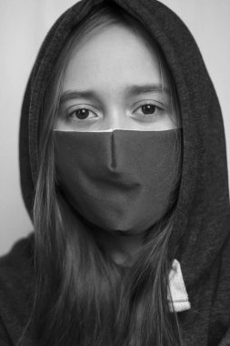 Yüzü maskeli bir genç öksürüyor. Coronavirus ve grip salgını konsepti. Maskeli bir kız. Siyah beyaz fotoğraf.