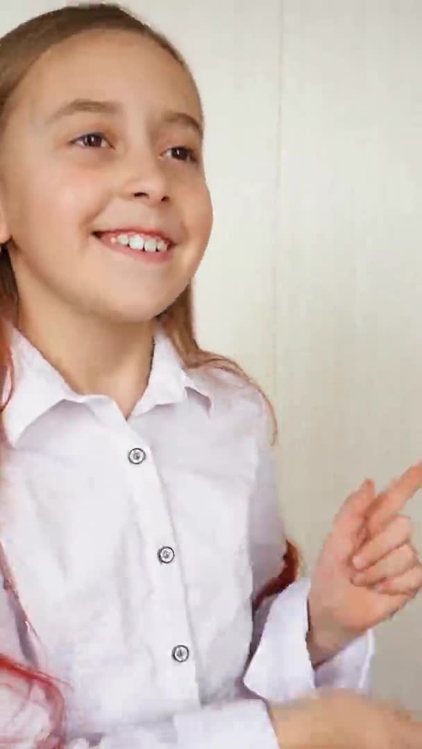 Joyeux fille dansant et souriant. L'adolescente positive dansant sur un fond clair. Vidéo verticale . — Video