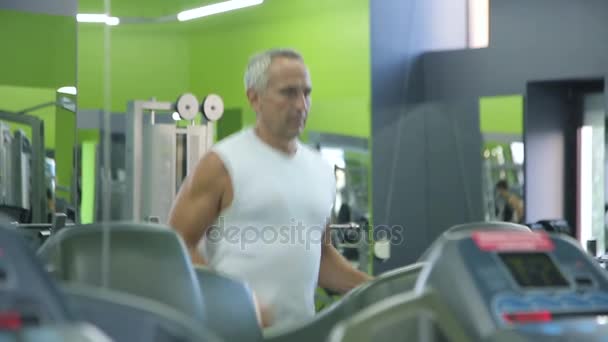 Old man runs on a treadmill — Stock Video