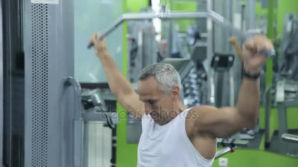 Old man is engaged on simulators in gym — Stock Video