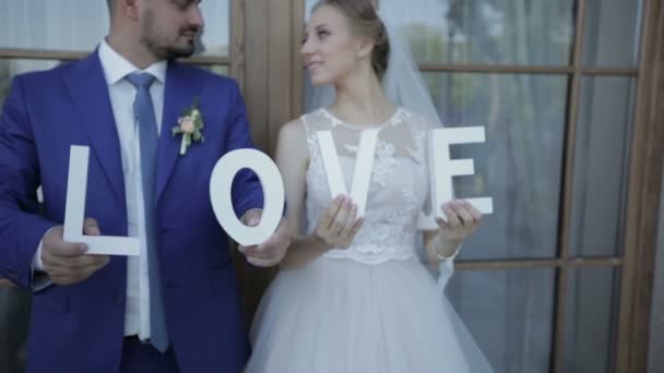 Recién casados sostienen la carta en sus manos en una sesión de fotos — Vídeo de stock