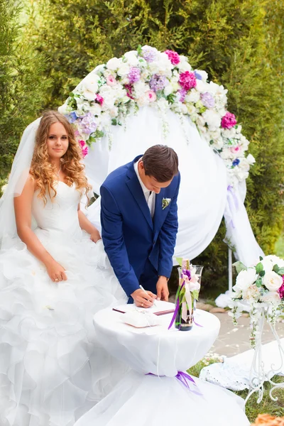Recién casados de pie cerca del arco de la boda —  Fotos de Stock