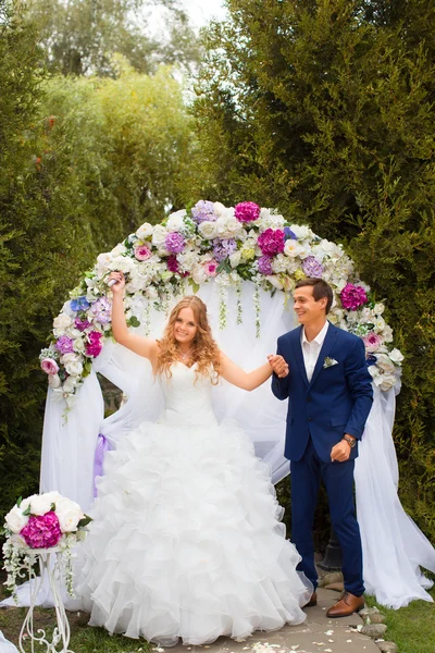 Nygifta står nära bröllop bågen — Stockfoto