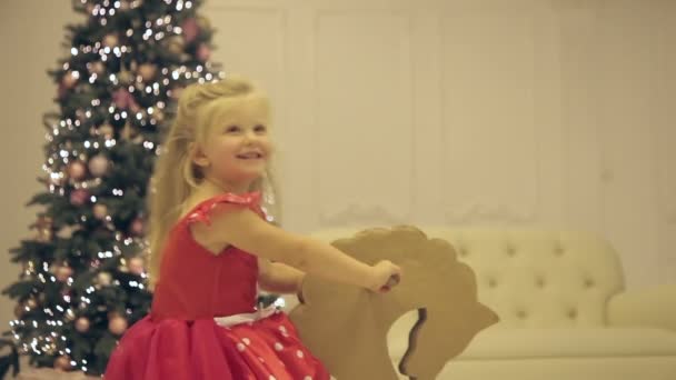 Маленькая девочка ездит на игрушке в канун Нового года — стоковое видео
