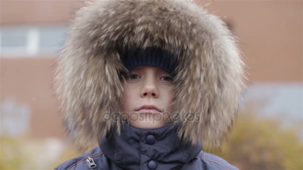 Portret van een jongen in de winter jas met capuchon op zijn hoofd — Stockvideo