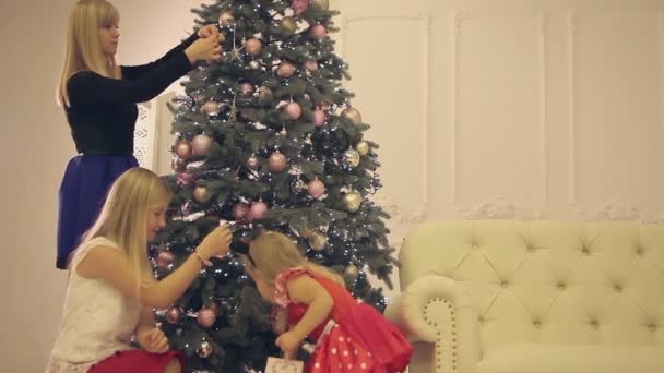 Мама з дочками прикрашає ялинку напередодні нового року — стокове відео