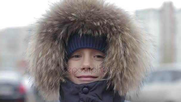 Portrait d'un garçon en veste d'hiver avec capuche sur la tête — Video