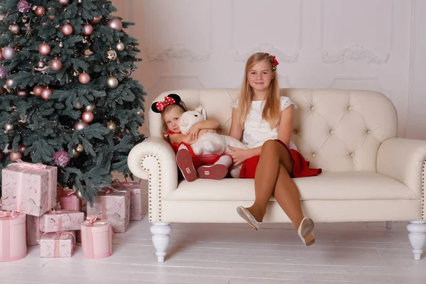 Siostry dziewczyny siedząc na kanapie z prezenty świąteczne w ręce — Zdjęcie stockowe
