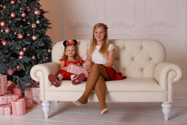 Irmãs meninas sentadas no sofá com presentes de Natal nas mãos — Fotografia de Stock