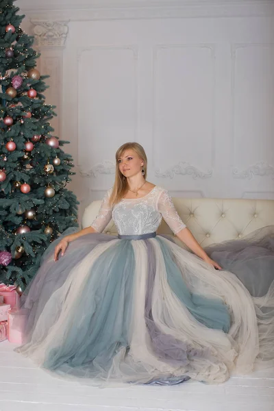 Блондинка в вечернем платье сидит на диване — стоковое фото
