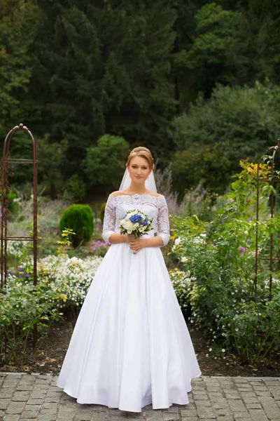 La ragazza in un abito da sposa con mazzo di fiori — Foto Stock