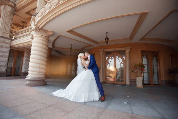 Recém-casados beijando de pé sob a varanda — Fotografia de Stock