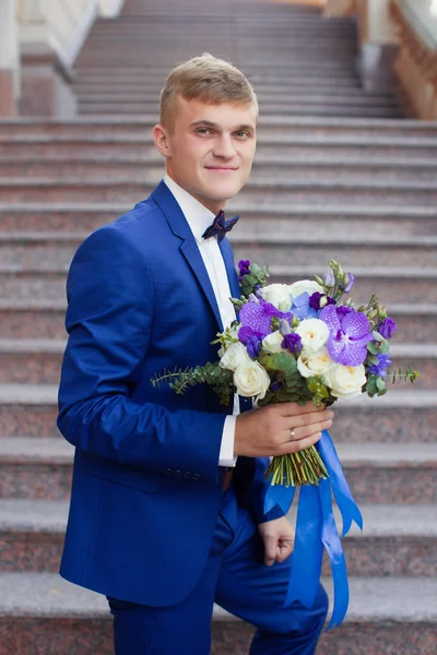 El novio en un traje azul con ramo — Foto de Stock