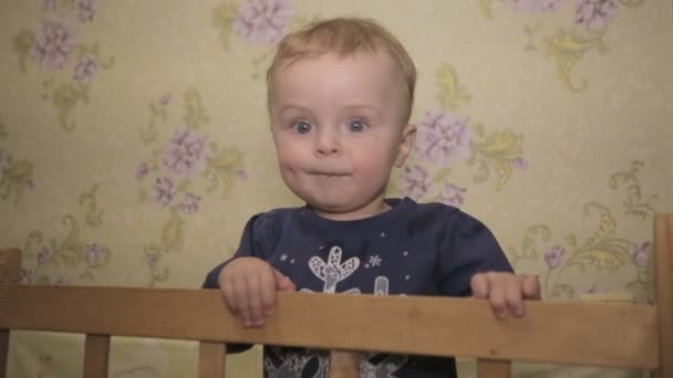 En liten pojke som står i barnsäng — Stockvideo