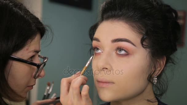 Maquillaje artista poniéndose maquillaje en los ojos modelos . — Vídeo de stock