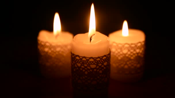 Tři hořící svíčky ve tmě — Stock video