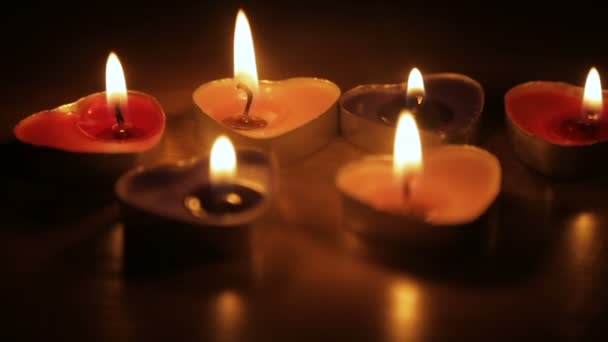 Свечи в форме сердец горят в темноте — стоковое видео