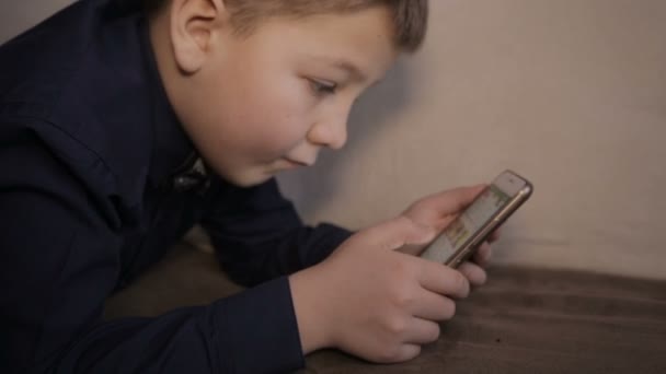 Un niño juega en el teléfono inteligente — Vídeos de Stock