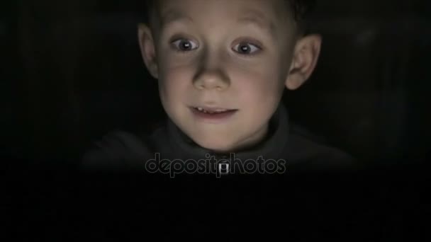 少年はコンピューターで暗闇の中で座っています。 — ストック動画
