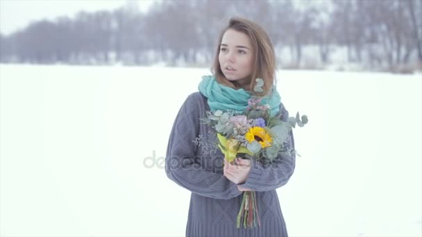 Szerelmes egy lányba, egy szürke pulóver egy csokor virágot egy befagyott tó . — Stock videók