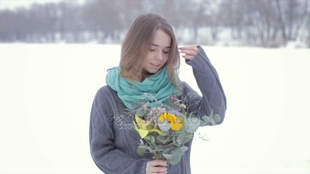 Liebe mit einem Mädchen in einem grauen Pullover mit einem Blumenstrauß auf einem zugefrorenen See .