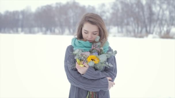 Любовь с девушкой в свитере с букетом цветов на замерзшем озере  . — стоковое видео
