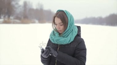 Neşeli kız kış sokakta telefonla konuşuyor. Ağır çekim