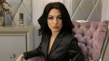 Seksi esmer bir sandalyede otururken poz. Dolu hd video