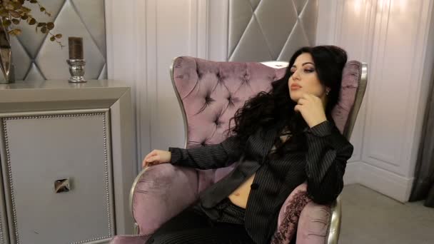 Σέξι μελαχρινή ποζάρουν ενώ κάθεται σε μια καρέκλα. Πλήρες βίντεο hd — Αρχείο Βίντεο