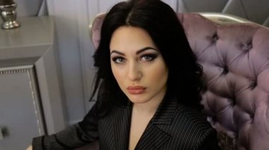 Seksi esmer bir sandalyede otururken poz. Dolu hd video