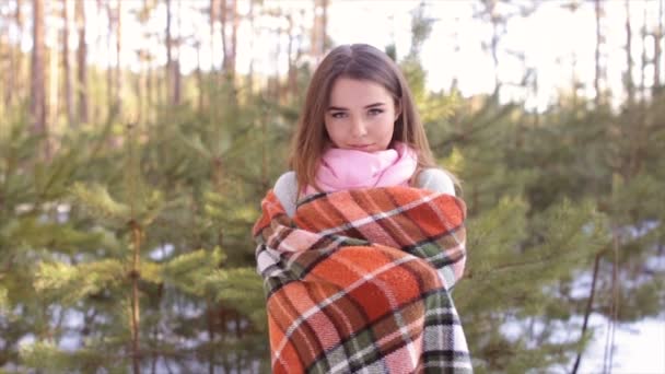 Το κορίτσι που είναι τυλιγμένη σε ένα καρό στο ξύλο τον χειμώνα. — Αρχείο Βίντεο