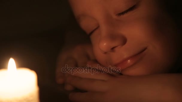 The boy is sleeping near a lighted candle. — Stock Video