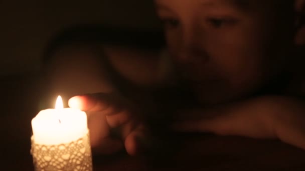 Le garçon touche la cire d'une bougie allumée — Video