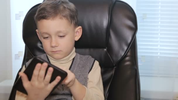Мальчик в кожаном кресле с табличкой в руках — стоковое видео