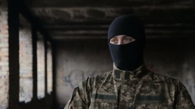 Bir adam kamuflaj ve eski terk edilmiş bir binada siyah maske