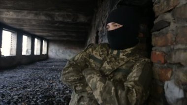 Bir adam kamuflaj ve eski terk edilmiş bir binada siyah maske