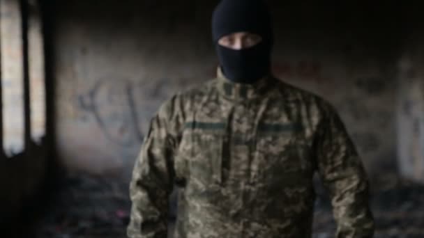 A man in camouflage and a black mask on an old abandoned building — Stock Video