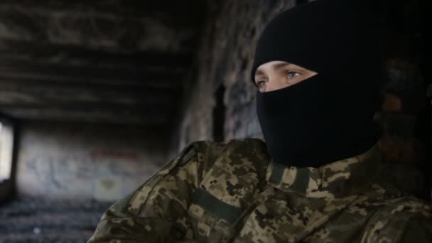 A man in camouflage and a black mask on an old abandoned building — Stock Video